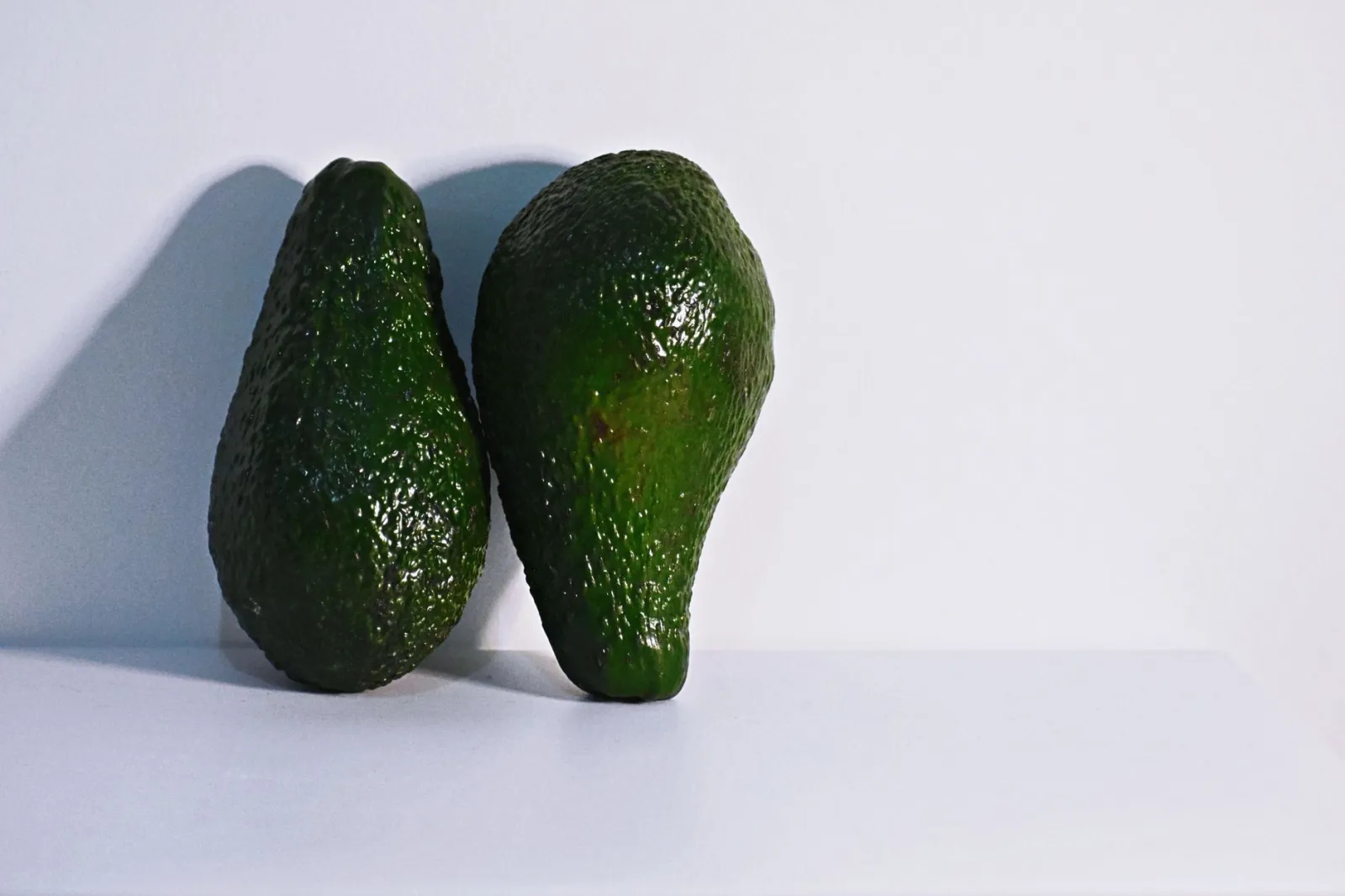 Two fresh avocados on a clean white background, highlighting healthy nutrition.