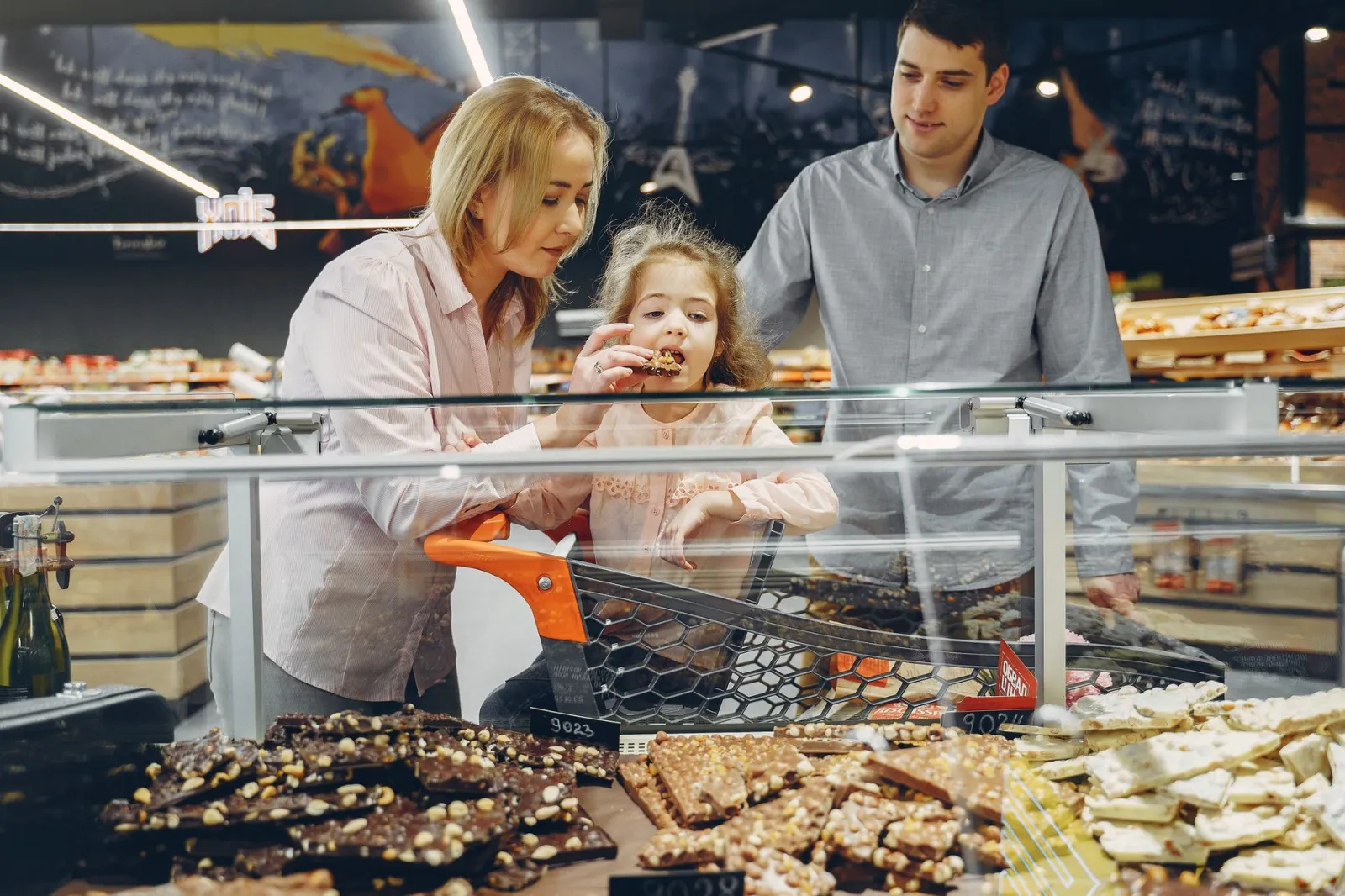 A family samples chocolates in a supermarket, sharing joy and togetherness.